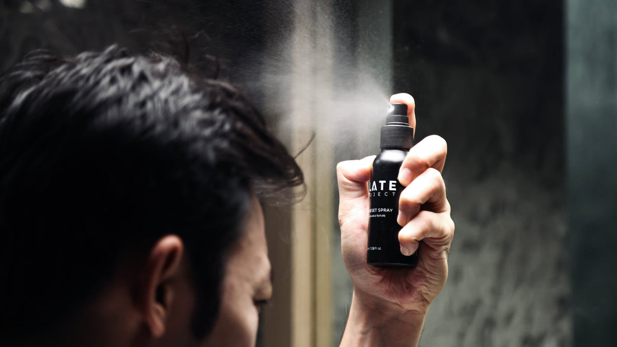 A man applies SLATE Hair Reset Spray during a morning grooming routine.